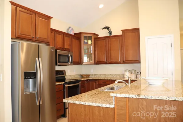 a kitchen with stainless steel appliances granite countertop a refrigerator a sink and a stove