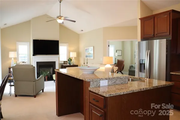 a kitchen with granite countertop stainless steel appliances a table chairs refrigerator and a television