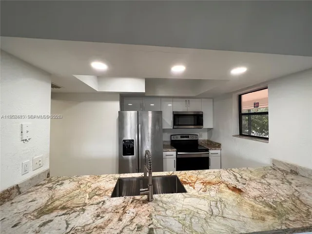 a large kitchen with a refrigerator and a sink