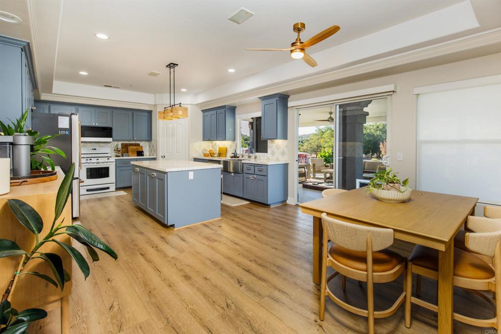 22544 Tombill Road Ramona, CA 92065 - Photo 1 of 74 a kitchen with stainless steel appliances a stove a refrigerator a kitchen island a dining table and chairs with wooden floor