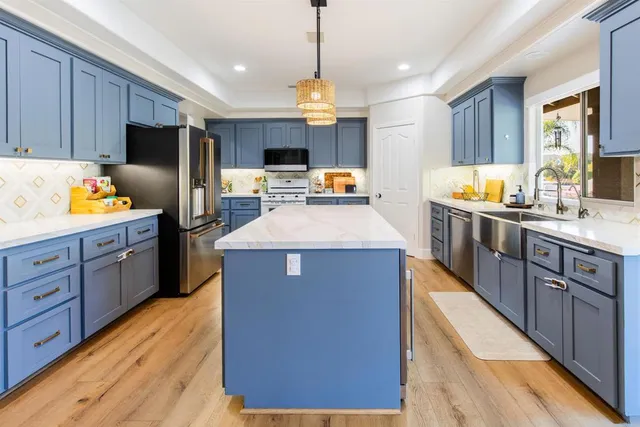 a kitchen with stainless steel appliances granite countertop a sink a stove and a wooden cabinets