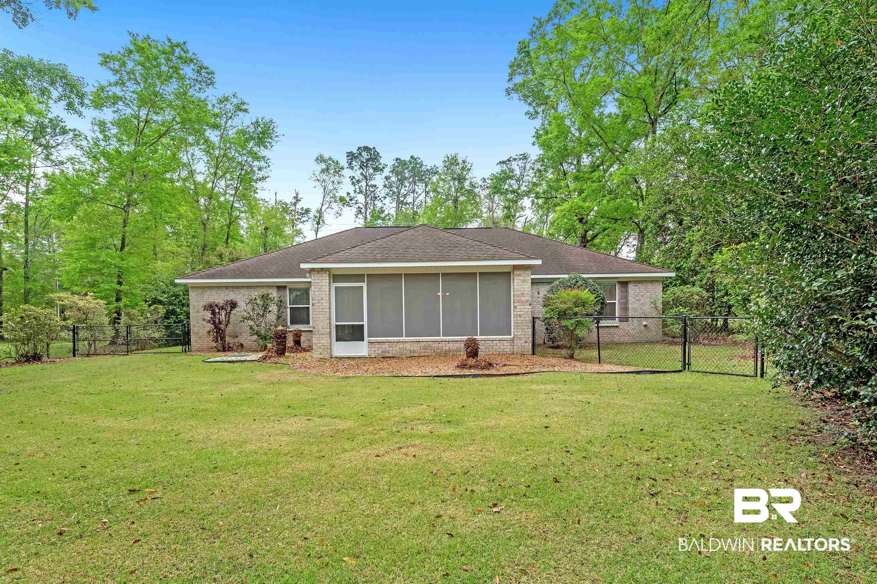 9908 Clarke Ridge Road Foley, AL 36535 - Photo 19 of 56 Back of property with roof with shingles, fence, brick siding, a sunroom, and a lawn