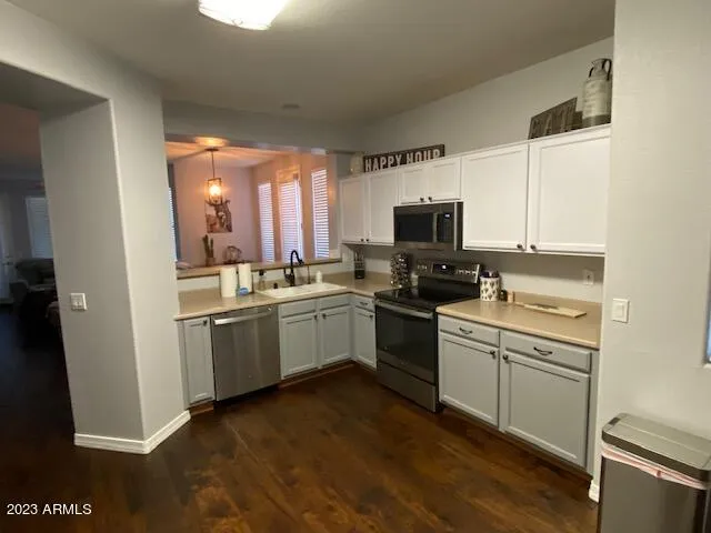 a kitchen with stainless steel appliances a refrigerator a stove and white cabinets with wooden floor