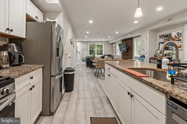 a kitchen with granite countertop a stove oven and white cabinets with wooden floor