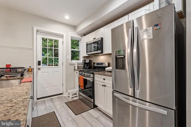 a large kitchen with stainless steel appliances granite countertop a lot of counter space and wooden floors