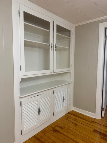 a view of an empty room with cabinet and wooden floor