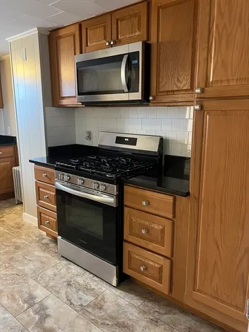 a kitchen with granite countertop cabinets stainless steel appliances and a wooden floor