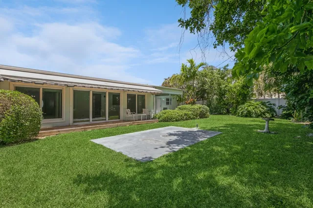 a view of a house with a yard and palm trees