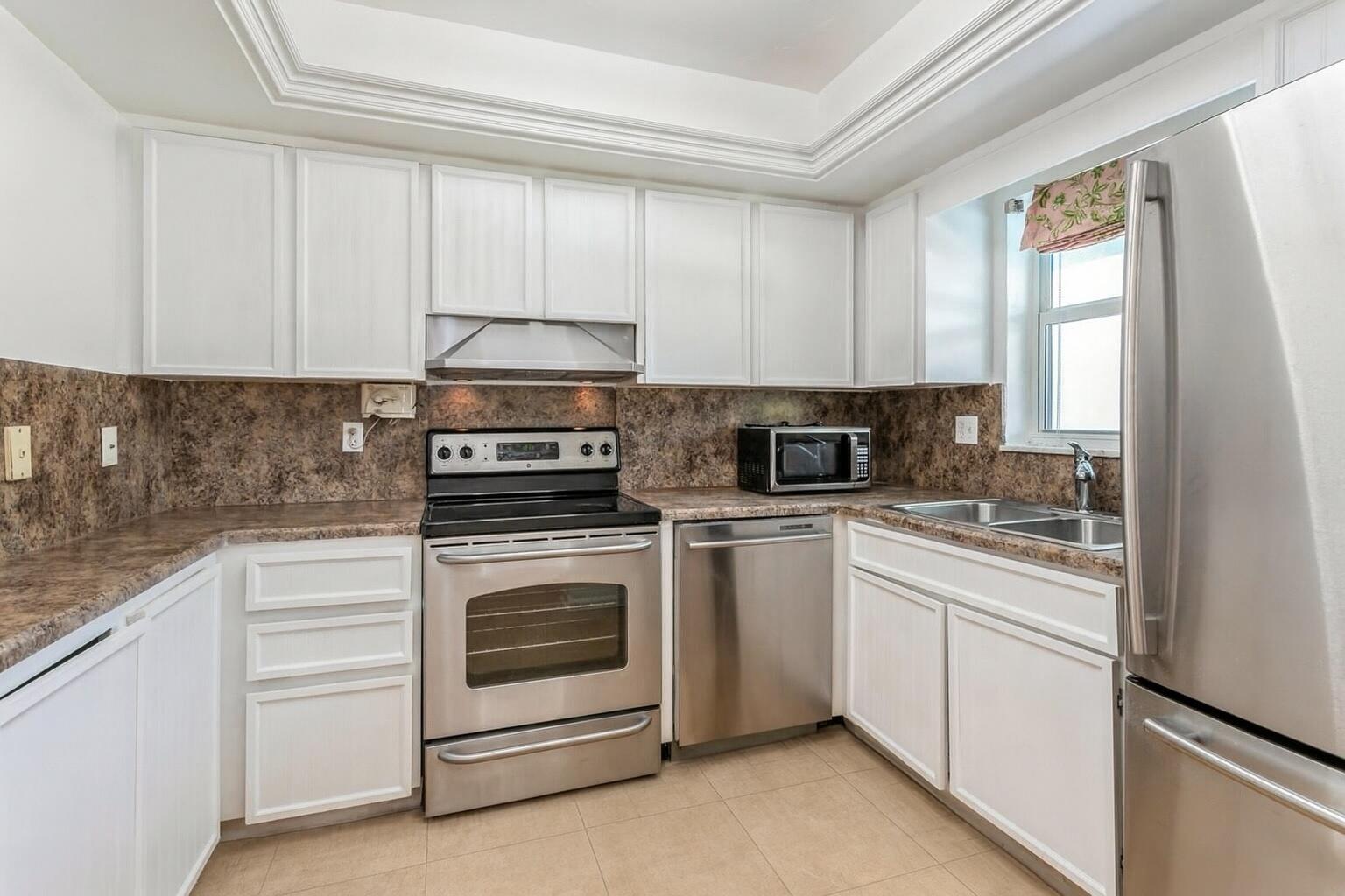 1217 Surf Road, Unit 2 Singer Island, FL 33404 - Photo 4 of 18 a kitchen with white cabinets and appliances