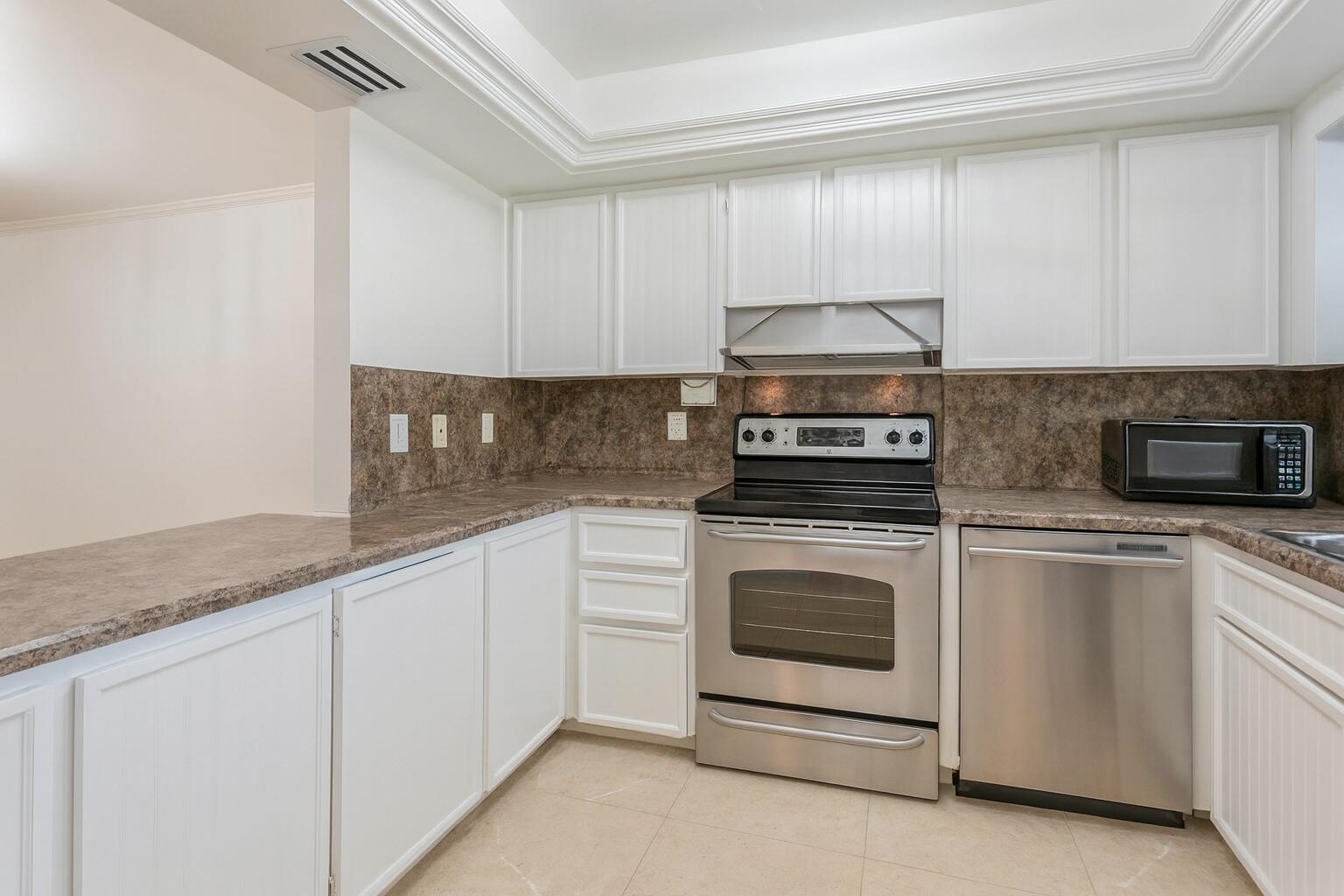 1217 Surf Road, Unit 2 Singer Island, FL 33404 - Photo 5 of 18 a kitchen with granite countertop white cabinets and white appliances