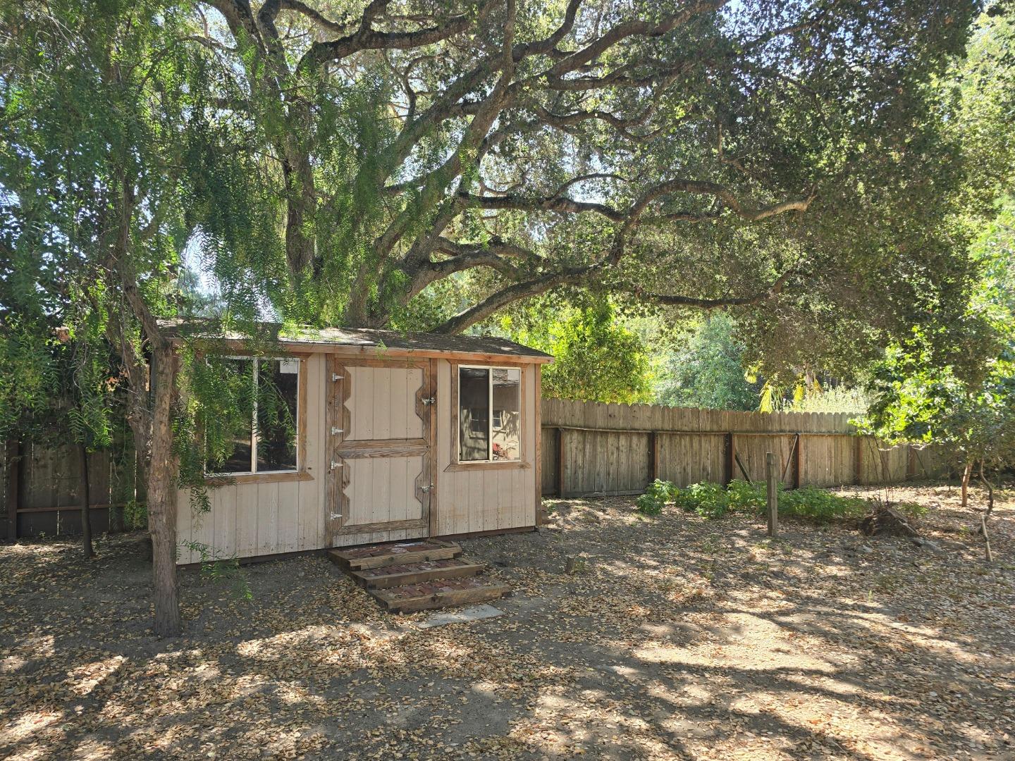 59 Boronda Road Carmel Valley, CA 93924 - Photo 10 of 43 a view of a small yard in front of a house with large trees and wooden fence