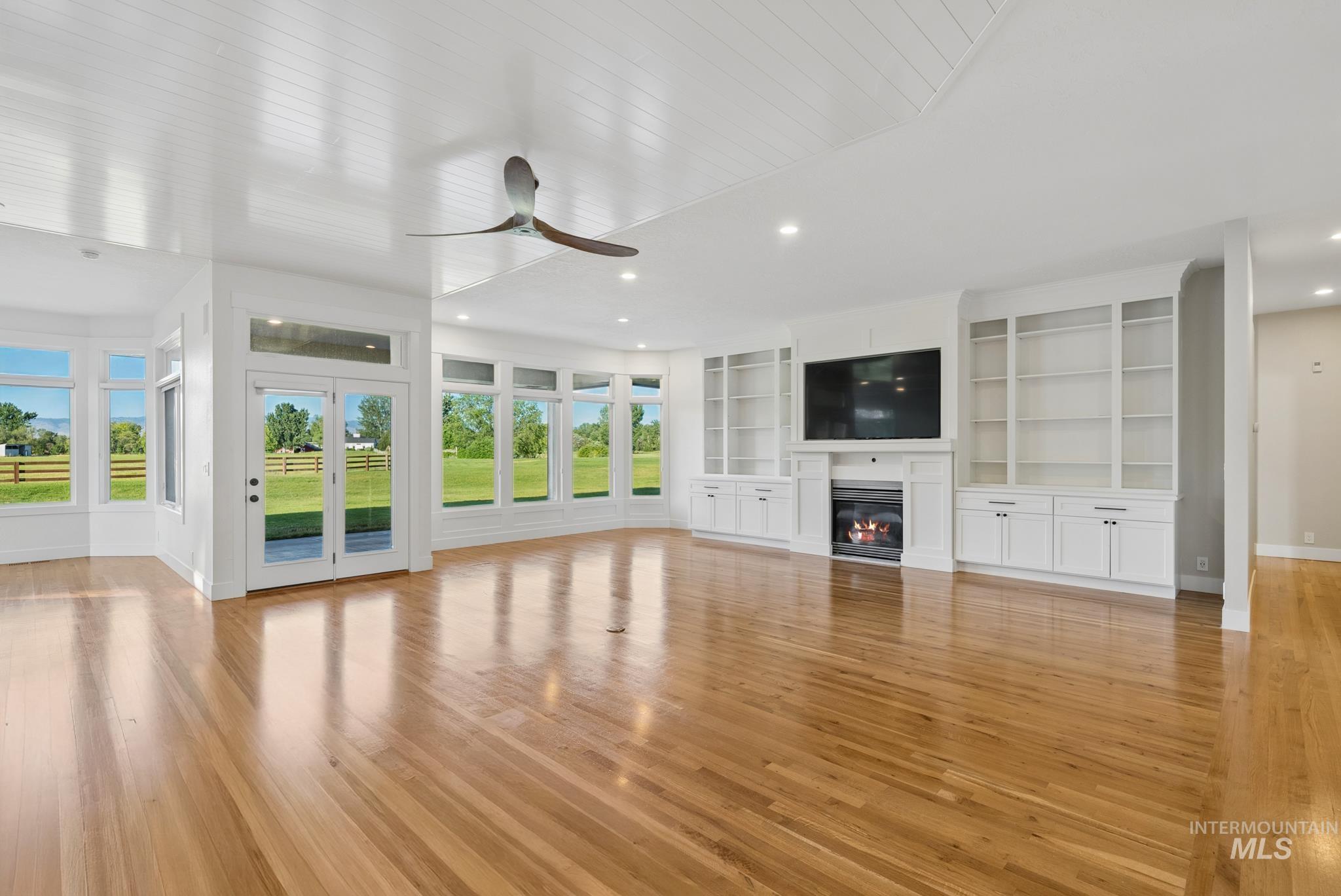 2050 Artesian Road Eagle, ID 83616 - Photo 7 of 49 Spacious interior featuring wood-finish flooring throughout, a built-in media center with a fireplace, extensive white cabinetry and shelving, and expansive windows offering outdoor views