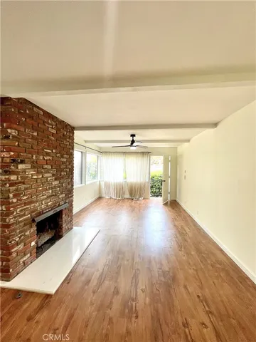 a view of empty room with wooden floor and fireplace
