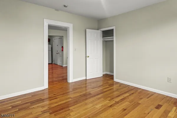 a view of an empty room with wooden floor and closet