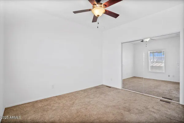 an empty room with closet and fan