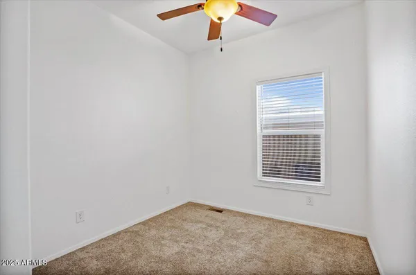 an empty room with a window and a ceiling fan