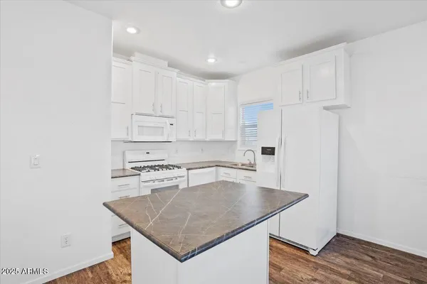a kitchen with stainless steel appliances granite countertop a sink a stove a refrigerator and white cabinets