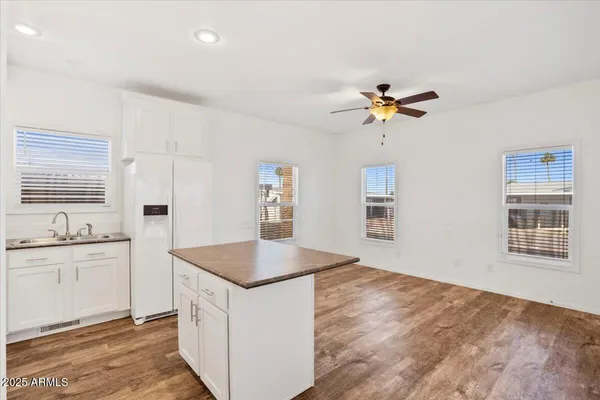 a kitchen with granite countertop a stove a sink a refrigerator and white cabinets with wooden floor