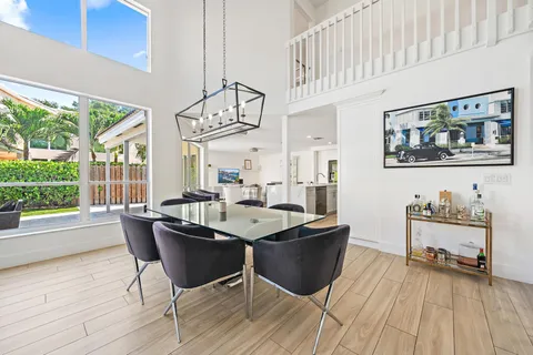 a dining room with wooden floor and large windows