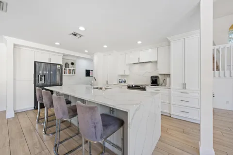 a large white kitchen with stainless steel appliances a table and chairs