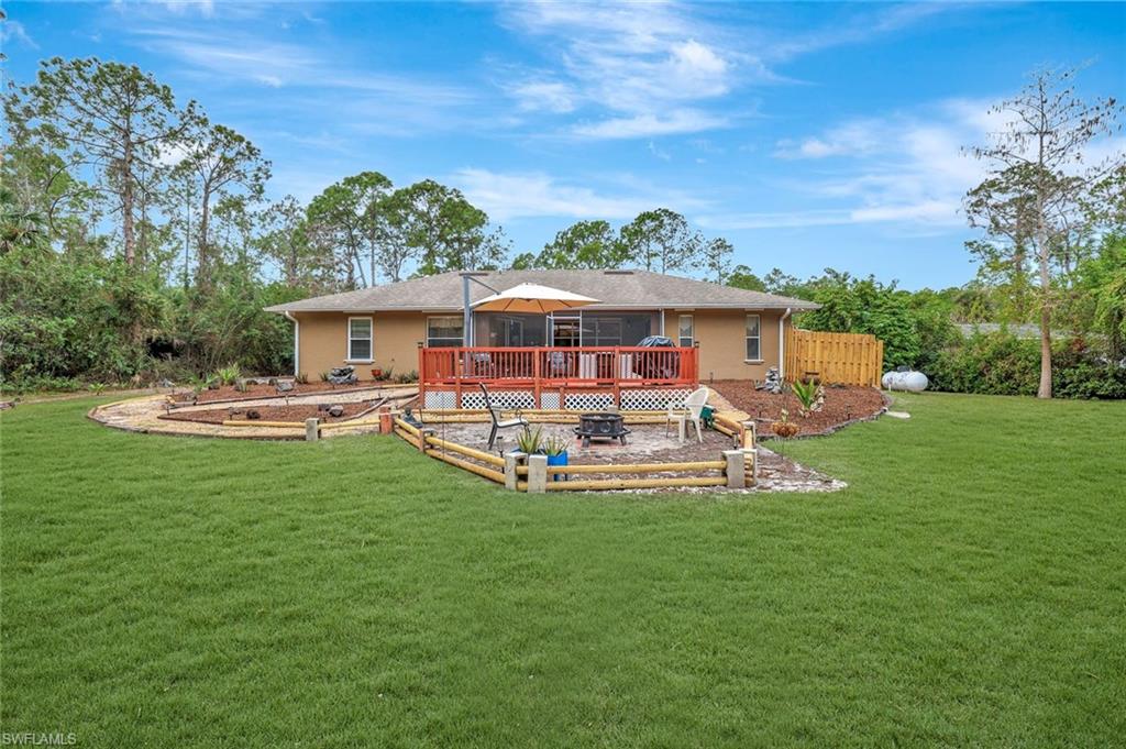 660 20th Street Southeast Naples, FL 34117 - Photo 15 of 17 Back of property with a lawn, a wooden deck, a garden, and stucco siding