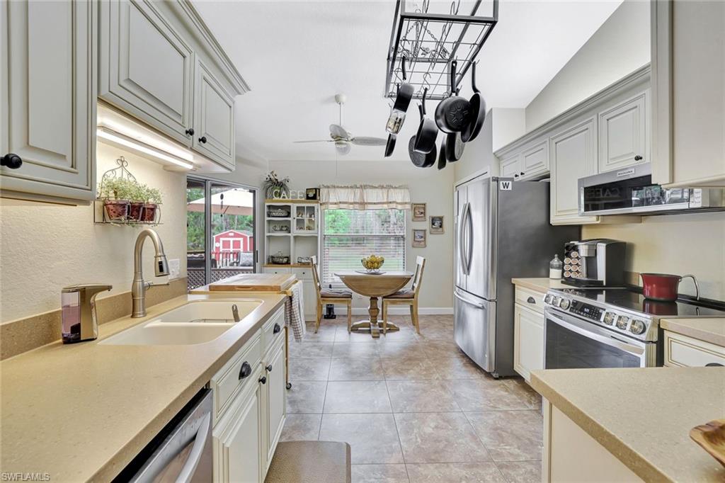 660 20th Street Southeast Naples, FL 34117 - Photo 4 of 17 Kitchen featuring stainless steel appliances, ceiling fan, light stone counters, extractor fan, and white cabinets