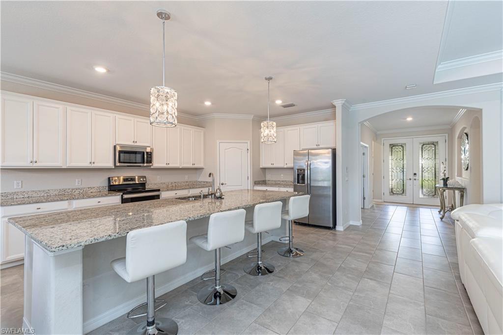2079 Vermont Lane Naples, FL 34120 - Photo 7 of 13 a kitchen with kitchen island granite countertop a table chairs microwave and cabinets