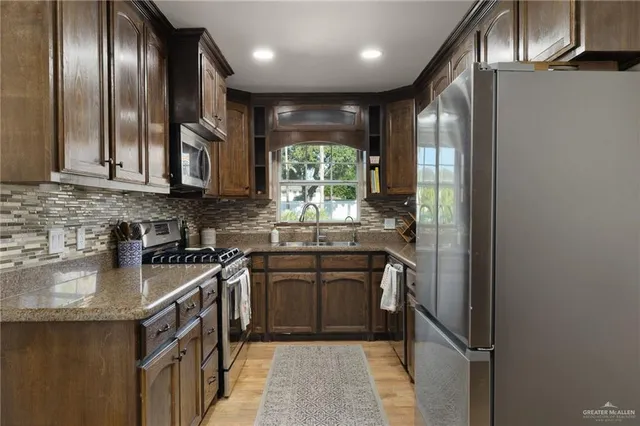a kitchen with stainless steel appliances granite countertop a stove a sink and a refrigerator