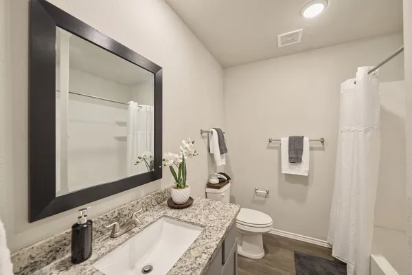 a bathroom with a granite countertop sink toilet and shower