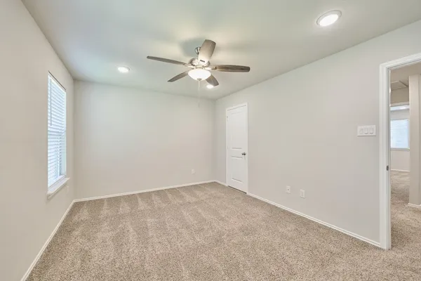 an empty room with windows and fan