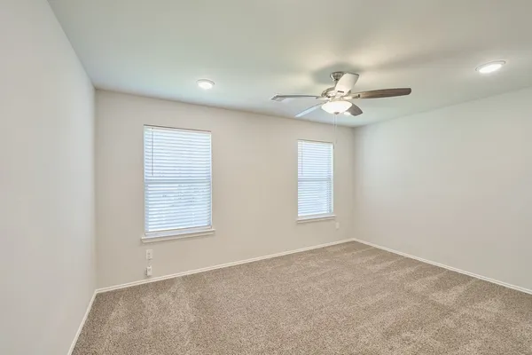 an empty room with windows and ceiling fan