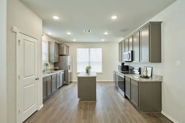a large kitchen with stainless steel appliances granite countertop a lot of counter space and wooden floors