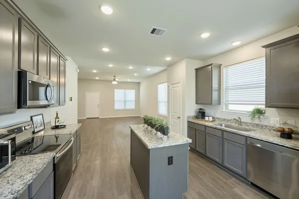 a large kitchen with stainless steel appliances granite countertop a sink stove and refrigerator