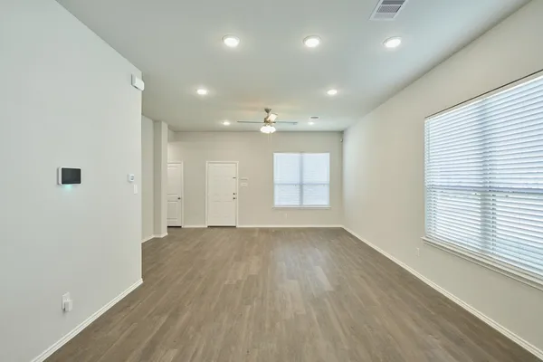 an empty room with wooden floor and windows