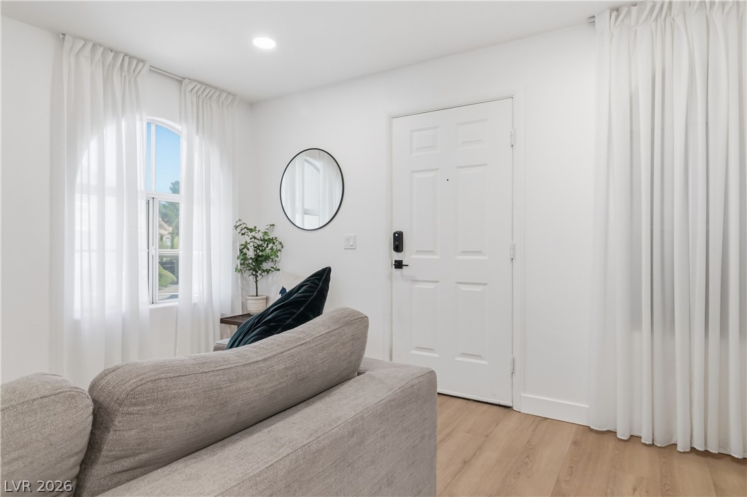 7950 West Flamingo Road, Unit 1180 Las Vegas, NV 89147 - Photo 4 of 26 Luminous living area showcasing a sleek entry door and natural wood-toned flooring.