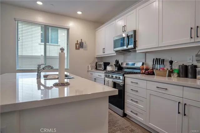 a kitchen with stainless steel appliances granite countertop a sink a stove and cabinets