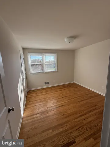 an empty room with wooden floor and window