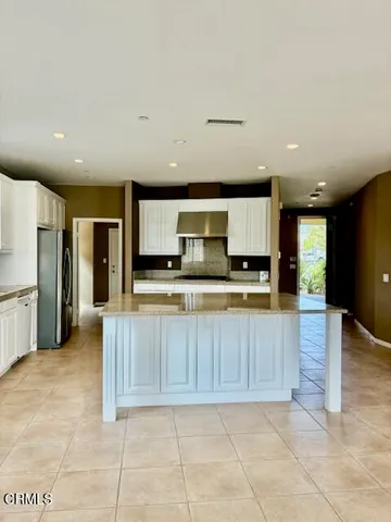a large kitchen with stainless steel appliances kitchen island granite countertop a refrigerator and a stove top oven