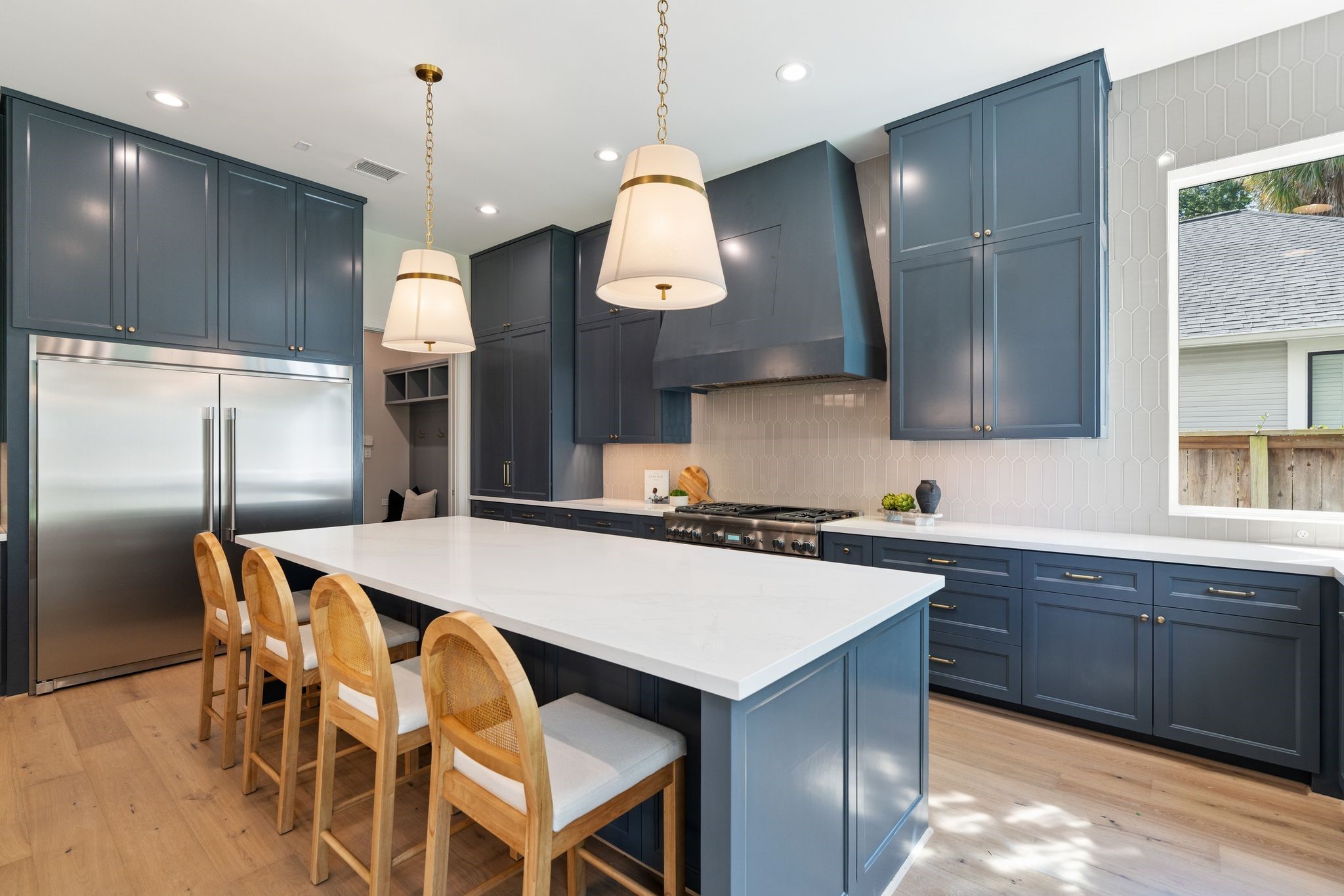 711 East 12th Street Houston, TX 77008 - Photo 19 of 47 A generous island with seating for four anchors this beautifully appointed kitchen. Brass pendants and a ceiling-height picket tile backsplash add warmth and texture.