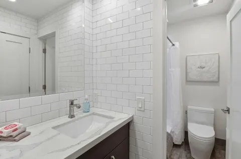 a bathroom with a granite countertop sink a toilet and shower