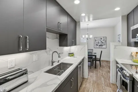 a kitchen with kitchen island granite countertop a sink cabinets and stainless steel appliances