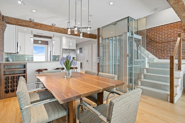 a kitchen with stainless steel appliances kitchen island granite countertop a table chairs and a refrigerator