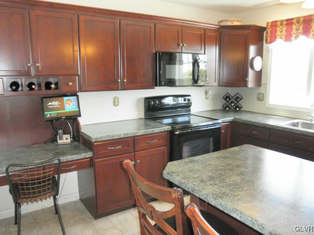 136 South Penn Dixie Road Nazareth, PA 18064 - Photo 18 of 30 a kitchen with kitchen island granite countertop wooden cabinets a stove a sink and a microwave