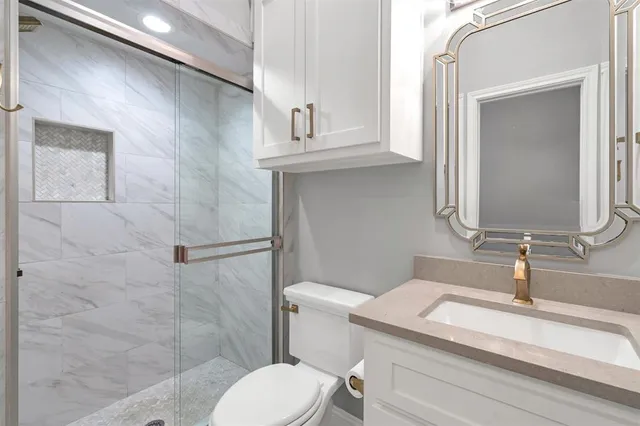 a bathroom with a granite countertop toilet sink and mirror