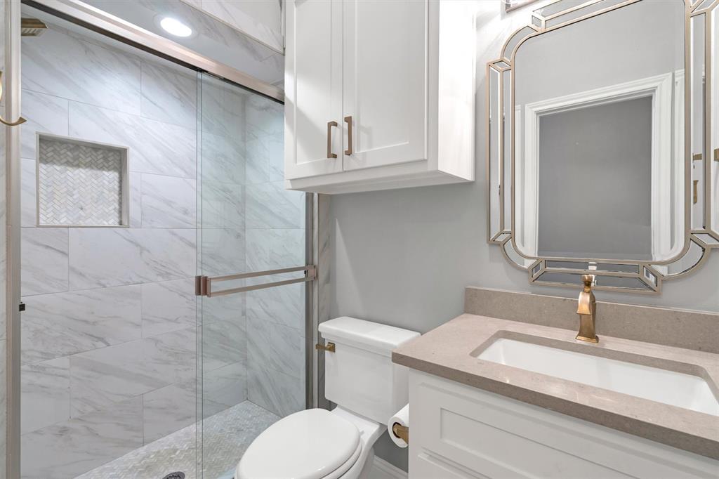 4511 Gilbert Avenue, Unit 108 Dallas, TX 75219 - Photo 18 of 25 a bathroom with a granite countertop toilet sink and mirror