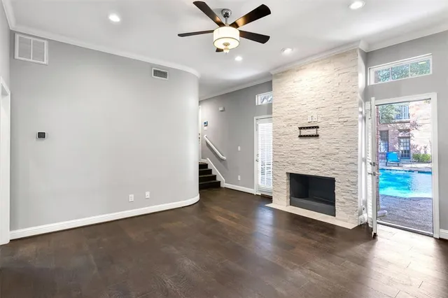 a view of an empty room with wooden floor a fireplace and a window