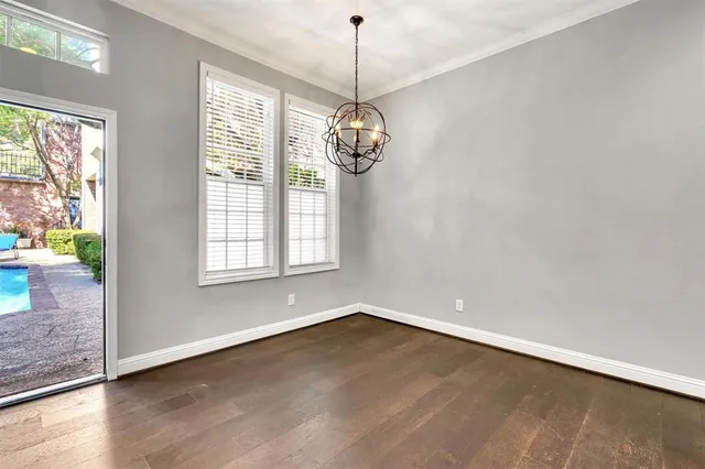 a view of a room with wooden floor chandelier and windows