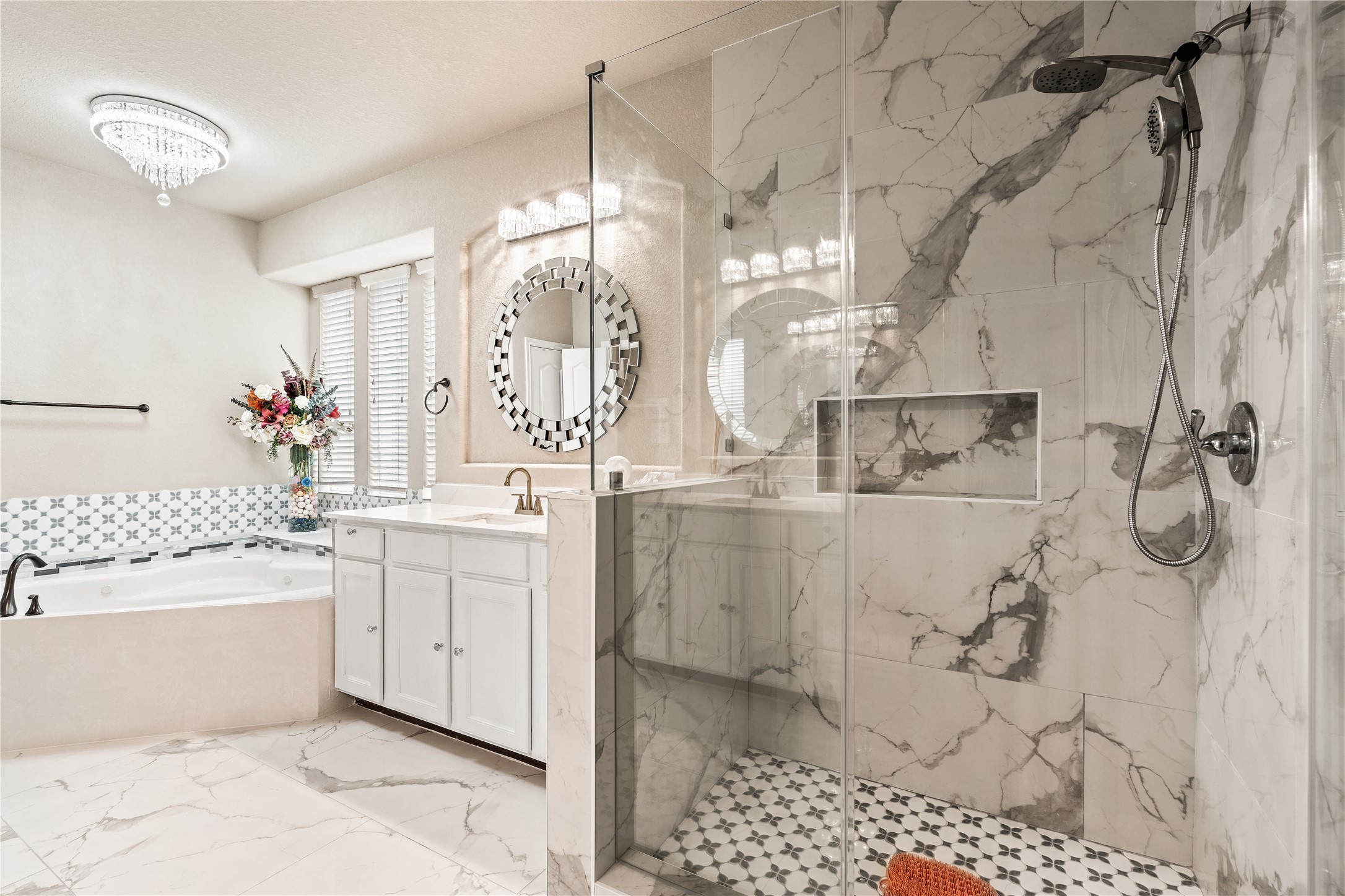 5802 Layton Meadows Lane Spring, TX 77379 - Photo 24 of 42 Master bathroom primary angle. Floor-to-ceiling marble tile, frameless glass walk-in shower, soaking tub with mosaic tile surround, crystal chandelier, round mirror. Luxury finishes throughout.