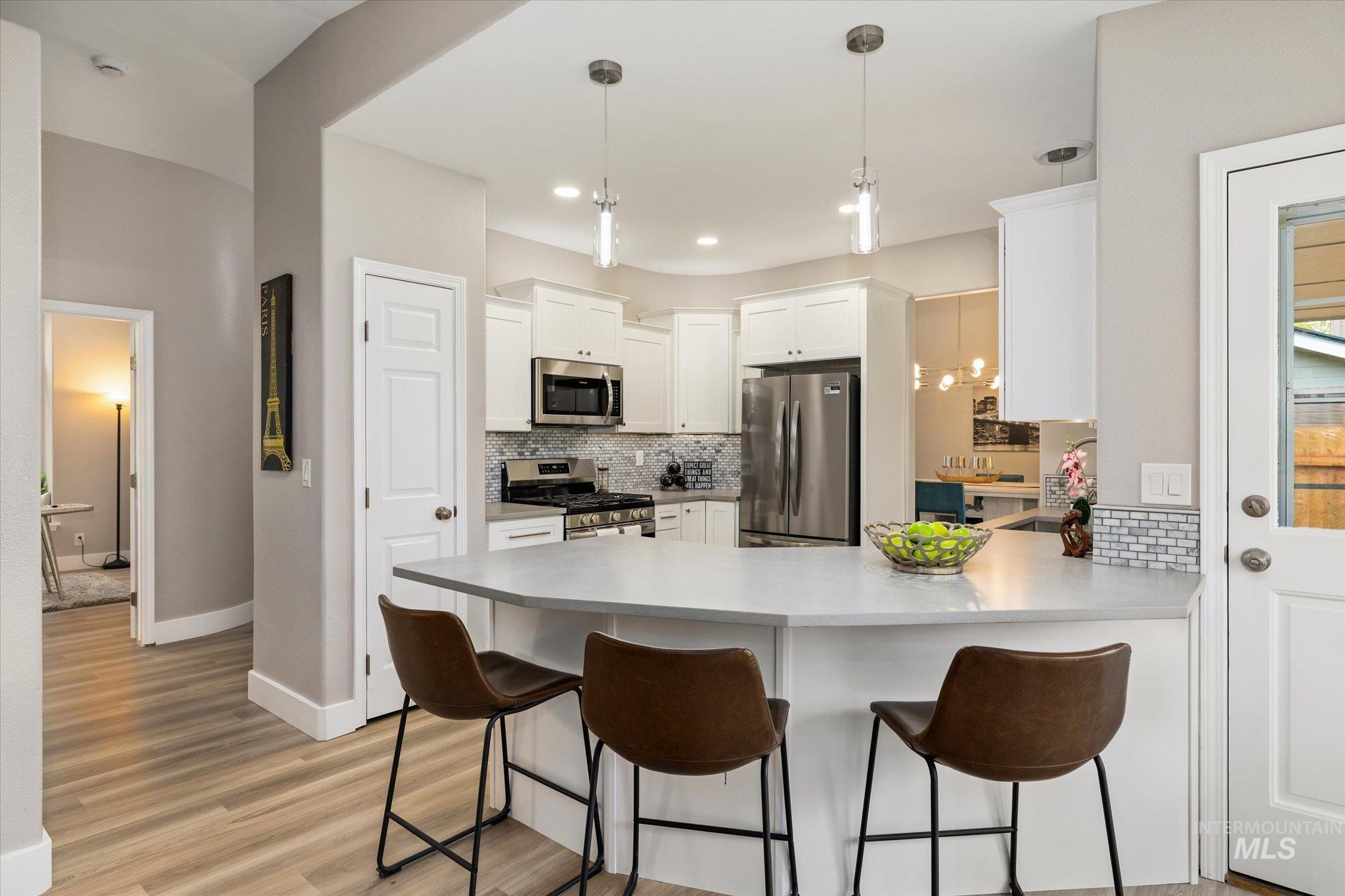 2250 North Amethyst Avenue Meridian, ID 83646 - Photo 21 of 50 Kitchen with a peninsula, a kitchen bar, white cabinetry, stainless steel appliances, and light countertops