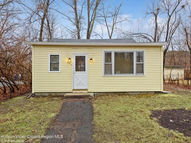 a view of a house with a small yard and large tree